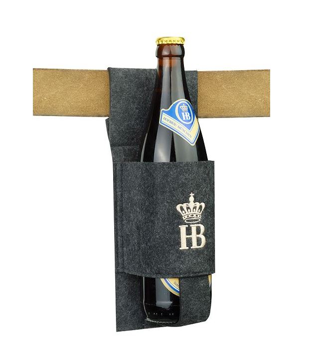Praktischer Flaschenhalter aus Filz in Dunkelgrau mit gesticktem HB-Logo und Krone, an einer Tischkante befestigt, mit einer Hofbräu Original Bierflasche