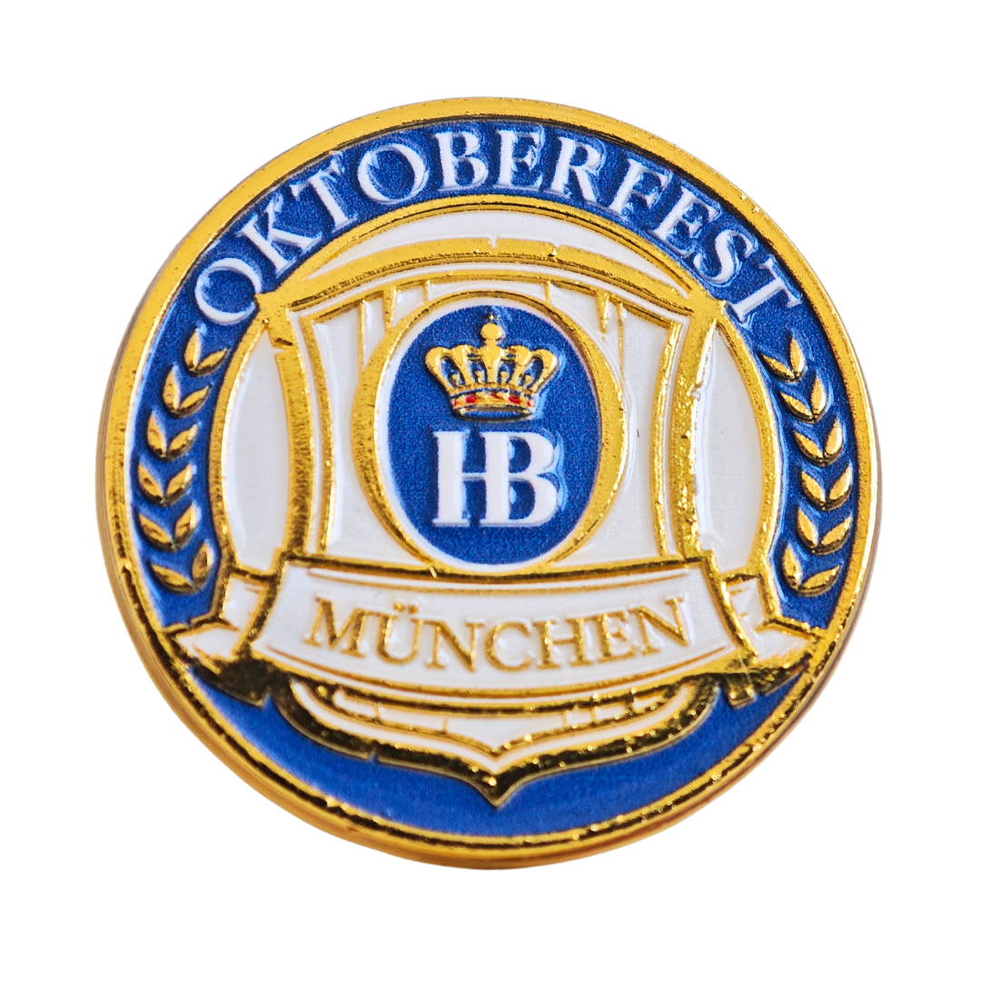 „Runder Magnet mit gold-blauem Oktoberfest-Logo, zentralem HB-Wappen mit Krone und den Schriftzügen ‚Oktoberfest‘ oben und ‚München‘ unten.“
