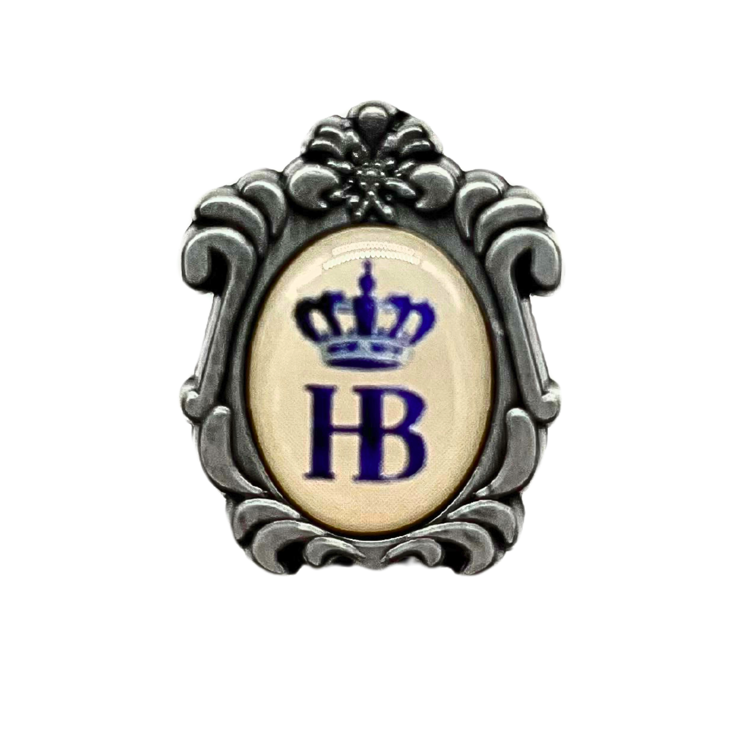 „Dekorativer Ansteckpin mit ovalem, cremefarbenem Hintergrund und einem blauen Emblem in der Mitte. Das Emblem zeigt die Buchstaben ‚HB‘ unter einer stilisierten Krone. Der Pin ist von einem kunstvoll verzierten Rahmen umgeben, der an antike Schmuckfassun